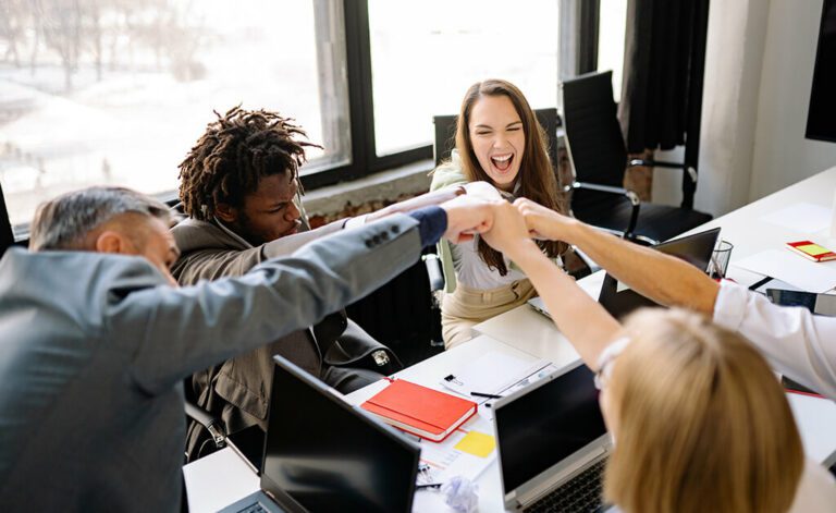 Group of excited professionals putting their hands together in the air as a successful business team.